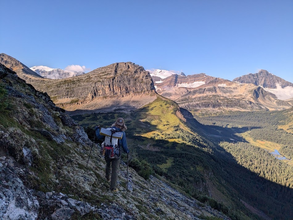 A hiker overlooking Watin pass and the valley below from a rocky mountain side