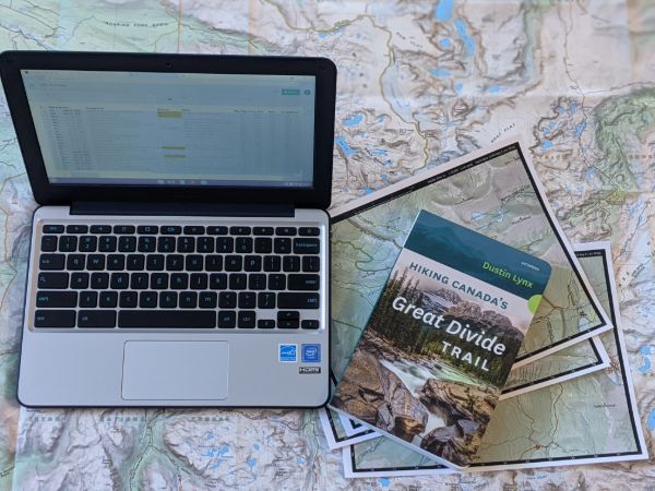 A laptop surrounded by maps and a GDT guidebook
