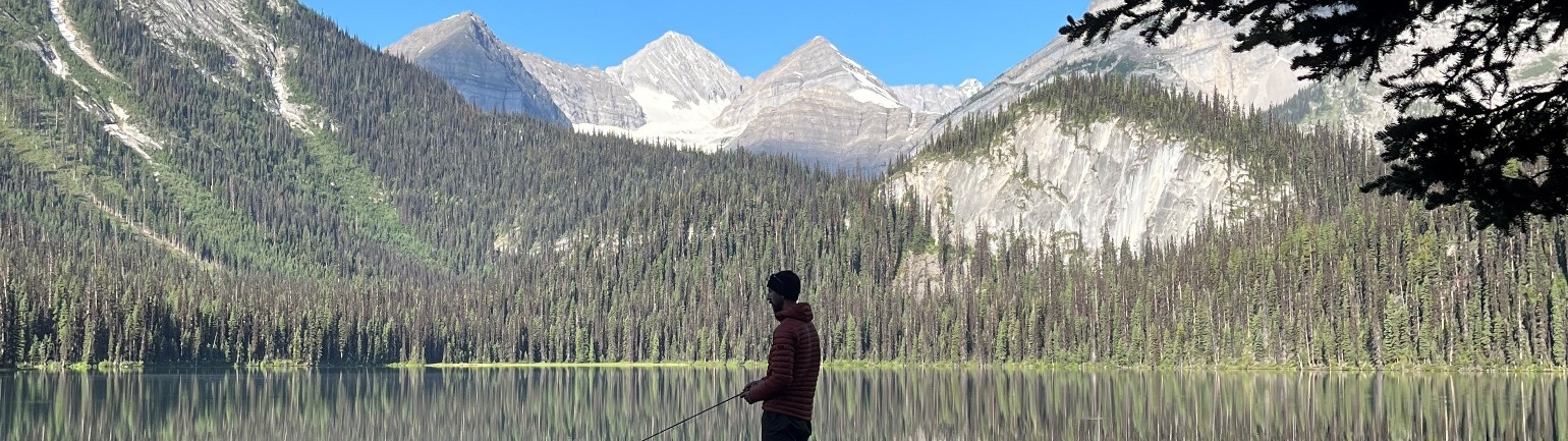 A hiker fishing at an alpine lake